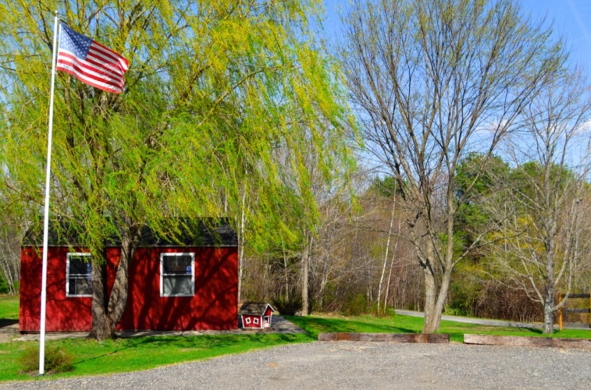 Red cabin, trees, and American flag.