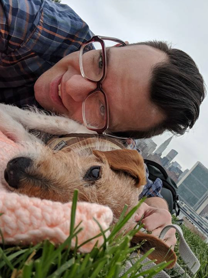 Man and dog lying on grass together.