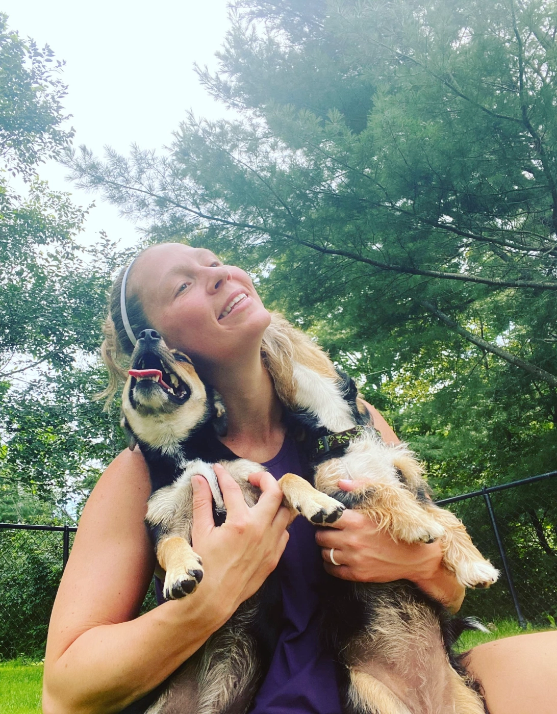 Woman joyfully hugging a playful dog outside. Woman joyfully hugging a playful dog outside.