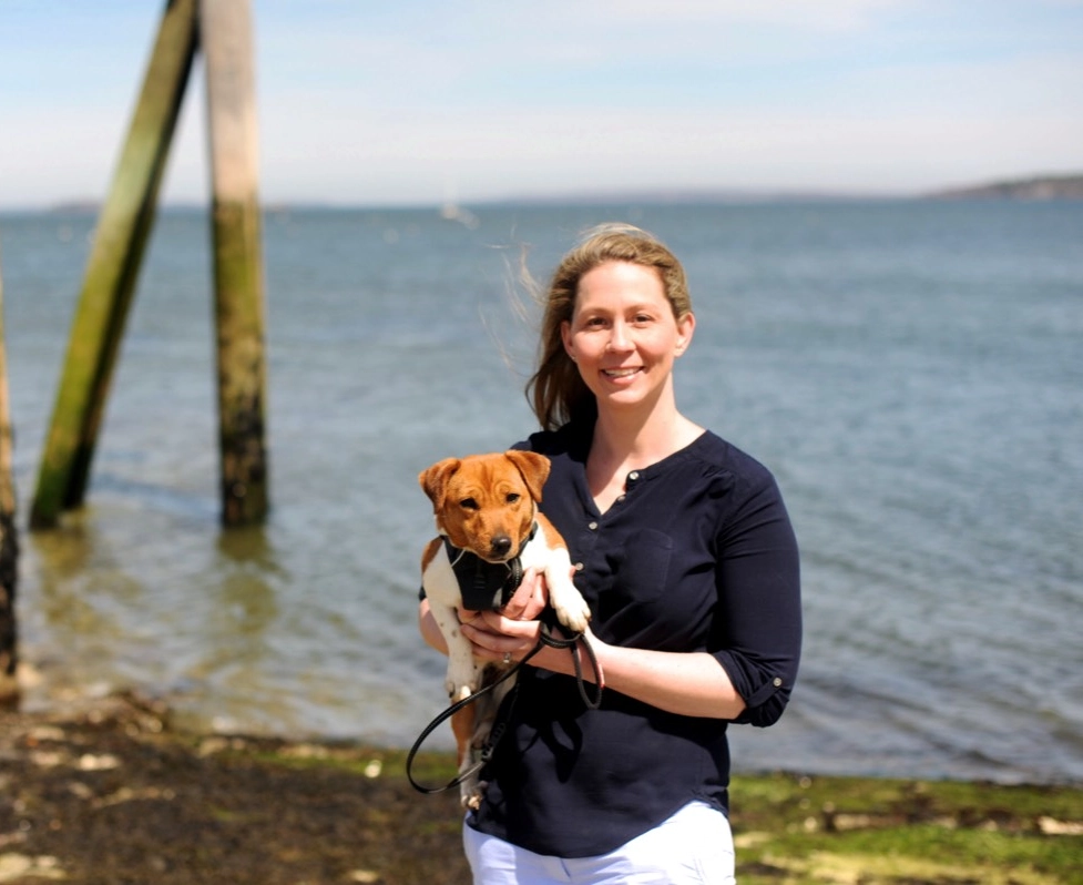 Woman holding dog by the seaside.