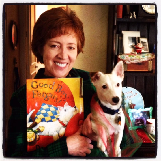 Woman holding dog and a children's book.