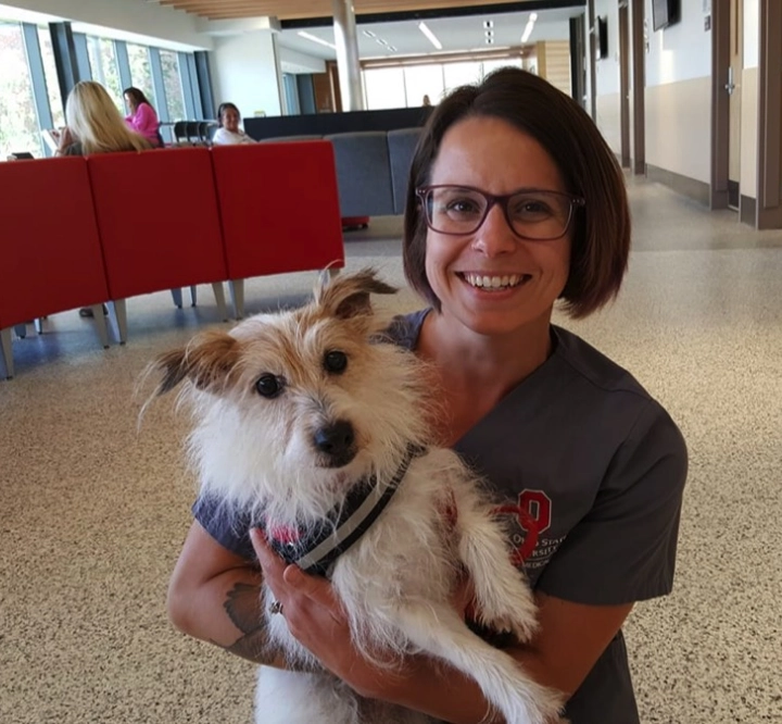 Woman holding a small white dog indoors. Woman holding a small white dog indoors.